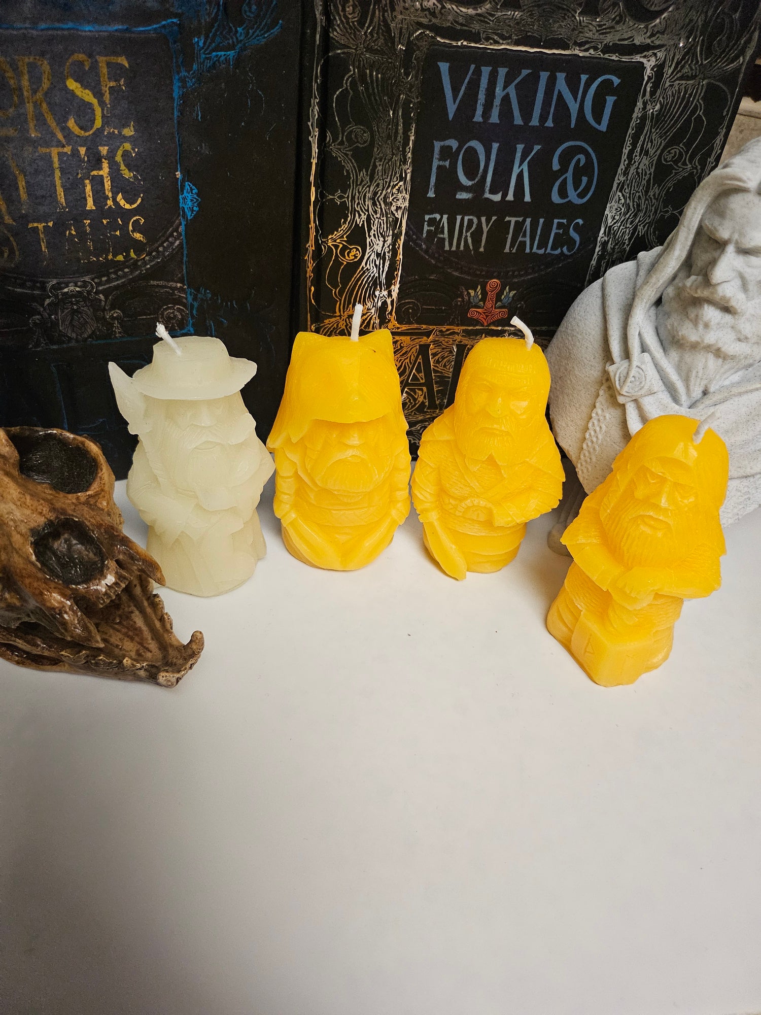 Yellow beeswax altar candles displayed with Viking Folk Co books, showing handcrafted Norse-inspired candle collection